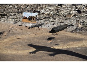 A before photo is placed on the remains of a building leveled in the Woolsey Fire as U.S. Secretary of the Interior Ryan Zinke casts a shadow while talking to firefighters at decimated Paramount Ranch Thursday, Nov. 15, 2018, in Agoura Hills, Calif.