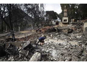 Roger Kelton searches through the remains of his mother-in-law's home leveled by the Woolsey Fire, Tuesday, Nov. 13, 2018, in the southern California city of Agoura Hills.