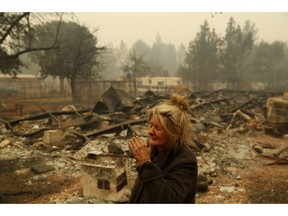 FILE - In this Nov. 9, 2018 photo, Cathy Fallon reacts as she stands near the charred remains of her home in Paradise, Calif. "I'll be darned if I'm gonna let those horses burn in the fire" said Fallon, who stayed on her property to protect her 14 horses, "It has to be true love."