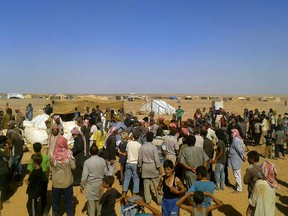 In this Aug. 4, 2016 file photo, people gather to take basic food stuffs and other aid from community leaders charged with distributing equitably the supplies to the 64,000-person refugee camp called Ruqban on the Jordan-Syria border. Statements issued by the United Nations and the Syrian Arab Red Crescent said their joint convoy reached Rukban camp and would deliver assistance to 50,000 people The convoy was supposed to arrive last week but was delayed due to logistics and security concerns. The U.N. said the operation is expected to take three to four days.