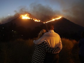 Roger Bloxberg, right, and his wife Anne hug as they watch a wildfire on a hill top near their home Friday, Nov. 9, 2018, in West Hills, Calif.