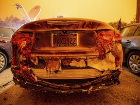 A scorched vehicle sits parked at a used car dealership after a wildfire burned through Paradise, Calif.