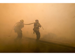 Firefighters battle a fire along the Ronald Reagan (118) Freeway in Simi Valley, Calif., Monday, Nov. 12, 2018.