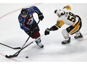 Colorado Avalanche center Nathan MacKinnon, left, loses control of the puck as Pittsburgh Penguins defenseman Kris Letang covers in the first period of an NHL hockey game Wednesday, Nov. 28, 2018, in Denver.