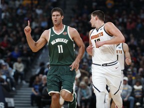 Milwaukee Bucks center Brook Lopez, left, gestures after hitting a three-point-basket over Denver Nuggets center Nikola Jokic in the first half of an NBA basketball game Sunday, Nov. 11, 2018, in Denver.