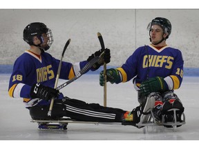 Humboldt Broncos hockey player Jacob Wassermann, left, and teammate Ryan Straschnitzki compare sticks during a sled hockey scrimmage at the Edge Ice Arena in Littleton, Colo., on Friday, Nov. 23, 2018. Both players were paralyzed from the waist down in the team's bus crash in April.
