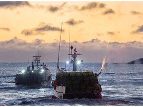 A fisherman sets off fireworks as boats head from West Dover, N.S. on November 28, 2017. Lobster fishing season in southwestern Nova Scotia will be off to a late start this year after officials postponed the day where fishermen were slated to drop their traps -- also known as "Dumping Day." The season was supposed to kick off on Monday, but Fisheries and Oceans spokeswoman Debbie Buott-Matheson says based on forecasted weather, the industry associations representing lobster fishing areas 33 and 34 decided it would be too risky to proceed as planned.