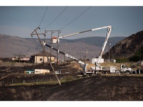 B.C. Hydro workers repair power lines above the remains of mobile homes destroyed by wildfire in Boston Flats near Ashcroft, B.C., on Sunday July 9, 2017. A report from BC Hydro says despite soaring numbers of powerful storms or wildfires that cause power outages, the Crown utility is still managing to respond quickly to trouble spots through the use of new technology.