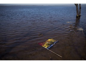 A New Brunswick flag floats in floodwater from the Saint John River in Waterborough, N.B., on May 13, 2018. The New Brunswick government will hire a consultant to review their response to the historic 2018 spring flood. Public Safety Minister Carl Urquhart says it's important to learn how to be better prepared for future events. About 12,000 properties were affected by the flood waters, and the government has received more than 1,100 applications for disaster financial assistance.