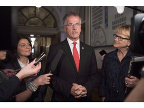 Quebec government MNA Guy Ouellette, centre, responds to reporters questions after they announced he was reintegrated in the government caucus, before question period at the legislature in Quebec City, Nov. 21, 2017.