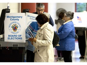 People cast their vote in the scanner machine at polling place during the U.S. midterm election Tuesday, Nov. 6, 2018, in Silver Spring, Md. Democrats were showing early signs of strength as results trickle in across the eastern United States in midterm elections widely expected to pass judgment on the first two years of Donald Trump's presidency.