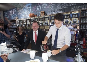 Liberal leader Justin Trudeau pours coffee for supporters next to local candidate Pierre Breton during a campaign stop at a coffee shop in Granby, Que., on October 6, 2015. The newly struck North American trade agreement will allow more American dairy products to enter Canada and, while it has yet to be ratified, it's already putting at least one MP from the governing Liberals in an awkward spot.