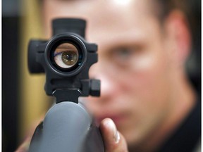 Patrick Deegan, a senior range officer at the Shooting Edge, looks through the scope of long gun at the store in Calgary on September 15, 2010. Investigations into whether gun licences should be revoked due to violent incidents or mental illness have faced "significant delays" that could endanger public safety, says an internal RCMP review. A lack of timely access to certain police and medical information has contributed to processing backlogs for firearms officers reviewing licence eligibility, warns the newly released audit report.