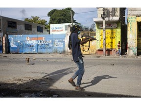 An armed civilian carries a weapon on during a shootout between rival gangs to take control of the Croix-des-Bossales market, on Boulevard Jean-Jacques Dessalines, a main commercial artery, in Port-au-Prince, Haiti, Wednesday, Nov. 21, 2018. The fight for control of the market, where vendors pay the controlling gang regular payments, erupted amid days of protests and a strike against alleged government corruption.