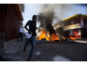 A youth runs past a burning roadblock during a strike that is part of protests demanding to know how Petro Caribe funds have been used by the current and past administrations, in Port-au-Prince, Haiti, Monday, Nov. 19, 2018. Much of the financial support to help Haiti rebuild after the 2010 earthquake comes from Venezuela's Petro Caribe fund, a 2005 pact that gives suppliers below-market financing for oil and is under the control of the central government.