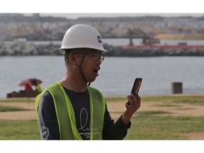 In this Saturday, Nov. 3, 2018 photo, a Chinese construction worker speaks on his mobile phone outside the Chinese funded sea reclamation project in Colombo, Sri Lanka. China and India are closely watching the constitutional crisis in Sri Lanka, the latest venue for their struggle for geopolitical supremacy in South Asia.