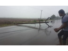 In this grab made from video provided by KK Productions, a man holds a brick to build a road diversion to help vehicles avoid an electric pole that fell after a cyclone struck Nagapattinam, in the southern Indian state of Tamil Nadu, Friday, Nov. 16, 2018. Cyclone Gaja hit the coast of southern India on Friday, killing more than 10 people and damaging homes after more than 80,000 residents were evacuated.
