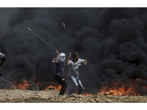 FILE - In this April 27, 2018 file photo, Palestinian protesters hurl stones at Israeli troops during a protest at the Gaza Strip's border with Israel. President Donald Trump's assertion that stones thrown by Latin American protesters at American troops should be treated as "rifles" has sparked debate about the appropriate response to rock throwing crowds -- particularly after Nigerian troops appeared to use his comments as justification for a deadly crackdown on demonstrators over the weekend. From the Gaza Strip to Africa to Europe, security forces have long dealt with stone throwers, albeit in very different ways.