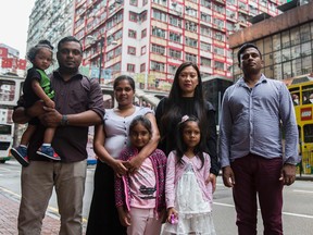 Sri Lankan refugee Ajith Puspa (R), Filipino refugee Vanessa Rodel (2nd R) with her daughter Keana, Sri Lankan refugees Nadeeka Nonis (3rd L) with her partner Supun Thilina Kellapatha (2nd L) and children Sethumdi (4th L) and Dinath (L) pose for a photo in front of the Torture Claims Appeal Board building in Hong Kong on July 17, 2017.