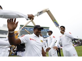 Sri Lanka's spin bowler Rangana Herath waves as he is greeted with an arch of bats while he enters the field for the last match of his test cricket career, the first test cricket match between Sri Lanka and England, in Galle, Sri Lanka, Tuesday, Nov. 6, 2018.