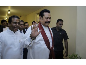 Sri Lanka's disputed Prime Minister Mahinda Rajapaksa, gestures as he arrives for a meeting with his supporting law makers at the parliamentary complex in Colombo, Sri Lanka, Thursday, Nov. 29, 2018. Sri Lankan lawmakers have approved a motion barring Rajapaksa from using state funds after he was defeated in a no confidence vote.