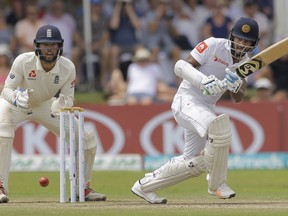 Sri Lanka's Dimuth Karunaratne plays a shot as England's Ben Foakes watches during the fourth day of the first test cricket match between Sri Lanka and England in Galle, Sri Lanka, Friday, Nov. 9, 2018.