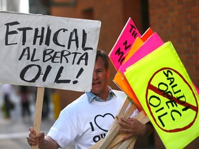A supporter carries placards outside the Kinder Morgan annual general meeting in downtown Calgary on May 16, 2018.