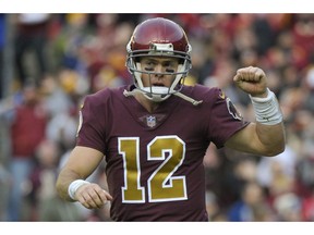 Washington Redskins quarterback Colt McCoy (12) celebrates running back Adrian Peterson's touchdown during the second half of an NFL football game against the Houston Texans, Sunday, Nov. 18, 2018 in Landover, Md.