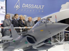 French President Emmanuel Macron, second left, listens to Dassault Aviation CEO Eric Trappier, center, while visiting the Paris Air Show in Le Bourget, north of Paris, June 19, 2017.