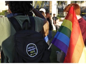 In this Wednesday, Oct. 31, 2018 photo, a student with a rainbow flag listens to speakers during a Vote for Our Lives rally at the University of Central Florida in Orlando, Fla. Nine months after 17 classmates and teachers were gunned down at their Florida school, Parkland students are finally facing the moment they've been leading up to with marches, school walkouts and voter-registration events throughout the country: their first Election Day.