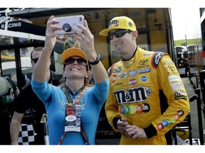 Kyle Busch, right, poses for a photo with a fan during practice for the NASCAR Cup Series auto race at the Homestead-Miami Speedway, Saturday, Nov. 17, 2018, in Homestead, Fla.