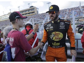 Martin Truex Jr. shakes hands with a fan before the NASCAR Cup Series championship auto race at Homestead-Miami Speedway, Sunday, Nov. 18, 2018, in Homestead, Fla.