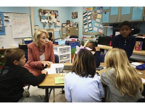 In this Nov. 26, 2018, photo, Secretary of Education Betsy DeVos chats with students at Cedar Grove Elementary to see how Hurricane Michael effected students and staff in Panama City, Fla. Since students in the Florida Panhandle county hardest hit by Hurricane Michael returned to classrooms within the past month, they've dealt with power outages, sporadic Internet, smaller enrollment, larger classes and schools sharing buildings.