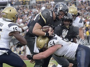 Central Florida quarterback McKenzie Milton (10) rushes for a 1-yard touchdown between Navy cornerback Noruwa Obanor (15) and linebacker Taylor Heflin (54) during the second half of an NCAA college football game Saturday, Nov. 10, 2018, in Orlando, Fla. UCF won 35-24.