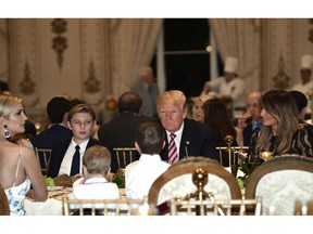 President Donald Trump, center, and first lady Melania Trump, right, sit with their family as they have Thanksgiving Day dinner at their Mar-a-Lago estate in Palm Beach, Fla., Thursday, Nov. 22, 2018. Ivanka Trump, left, and Barron Trump, second from left, attend.
