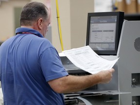 An employee at the Broward County Supervisor of Elections office runs ballots through a machine as he counts ballots from the mid-term election, Thursday, Nov. 8, 2018, in Lauderhill, Fla.