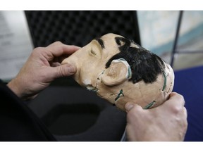 FBI Special Agent in Charge John F. Bennett examines a newly 3D printed decoy head used in a famous 1962 prison escape during a news conference on Alcatraz Island Thursday, Nov. 15, 2018, in San Francisco. The FBI has created replicas of decoy heads used by prisoners to mount their infamous escape from Alcatraz Island in 1962. Authorities on Thursday unveiled 3D printed replicas of the decoys that inmates had constructed with soap, plaster and human hair to distract guards from their plan. Authorities say inmates Frank Morris and John and Clarence Anglin placed the decoys in their beds before climbing through the wall to escape the island prison in San Francisco Bay. The men were never found.