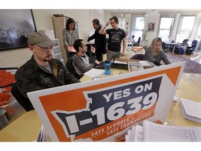 FILE - In this Thursday, Oct. 4, 2018, file photo, staff members for the Yes on I-1639 campaign, a gun safety initiative, prepare campaign materials at their headquarters in Seattle. The National Rifle Association is suing to block the new, voter-approved gun control measure in Washington state. The NRA and the Bellevue, Washington-based Second Amendment Foundation sued in U.S. District Court in Seattle on Thursday, Nov. 15, 2018, saying the measure violates the 2nd Amendment and strays into the regulation of interstate commerce, which is the province of the federal government.