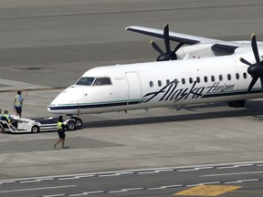 File - In this Aug. 13, 2018 file photo, a Horizon Air Q400 turboprop airplane, part of Alaska Air Group, is moved into position by airport workers at Seattle-Tacoma International Airport in SeaTac, Wash. The plane is the same model of aircraft stolen from the airport by an airline ground agent which later crashed into crashed into a small island in the Puget Sound, killing the man. Authorities say the Seattle airport ground crew worker who stole an empty commercial airplane had apparently searched online for flight instruction videos before he took off on a dizzying ride that soon crashed into a small island. The FBI announced Friday, Nov. 9, 2018, that it's concluding the investigation into the August 10 incident after determining that Richard Russell, 28, of Sumner, Washington, acted alone from Seattle-Tacoma International Airport.