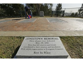 In this Thursday, Oct. 25, 2018, photo, former Peoples Temple member Jim Jones Jr. places bleached rocks around the edges of the Jonestown victim memorial in the Evergreen Cemetery in Oakland, Calif. Ceremonies were held at the cemetery to mark the mass murders and suicides 40 years earlier of more than 900 Americans orchestrated by the Rev. Jim Jones at a jungle settlement in Guyana, South America. The unclaimed or unidentified remains of more than 400 victims of the Jonestown tragedy on Nov. 18, 1978, are buried at the cemetery.
