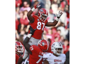 Georgia wide receiver Tyler Simmons gets a hoist from Isaiah Wilson after scoring a touchdown against Massachusetts during the first half of an NCAA college football game, Saturday, Nov. 17, 2018, in Athens, Ga.