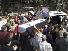 FILE - In this Thursday, July 26, 2018, file photo, released by the Syrian official news agency SANA, mourners carry a coffin of more than 200 people who were killed a day earlier by a series of suicide bombings launched by the Islamic State's fighters on the eastern and northern countryside of the southern province of Sweida during a mass funeral. Syrian troops have liberated 19 women and children hostages held by the Islamic State group since July in a military operation in the country's center, ending a crisis that has stunned Syria's Druze minority, state media reported Thursday, Nov. 8, 2018. (SANA via AP, File)
