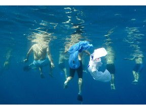 In this Sunday, Nov. 18, 2018, photo, plastic bags float as swimmers prepare to emulate sea creatures in an effort to send a message that pollutants such as bottles and plastic bags will entangle marine animals, next to the rocky coastal area in the Mediterranean Sea on the Beirut coastline, Lebanon.