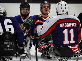 Humboldt Broncos hockey players Jacob Wassermann, left, and Ryan Straschnitzki laugh with Jerry DeVaul, (11), a member of the Warrior Avs sled hockey team, after scrimmage at the Edge Ice Arena in Littleton, Colo.