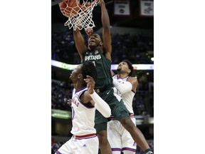 Michigan State forward Aaron Henry, center, dunks between Kansas defenders Marcus Garrett, left, and Dedric Lawson during the first half of an NCAA college basketball game at the Champions Classic in Indianapolis on Tuesday, Nov. 6, 2018.