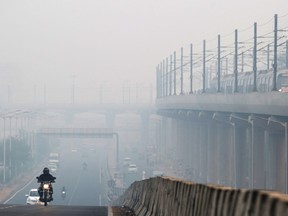 Vehicles traveling along a smog-covered road as a train traveling along a section of an elevated track are shrouded in smog in Delhi, India, on Nov. 9, 2018. MUST CREDIT: Bloomberg photo by Ruhani Kaur