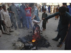 Pakistani protesters burn a poster image of Christian woman Asia Bibi, who has spent eight-years on death row accused of blasphemy and acquitted by a Supreme Court, in Hyderabad, Pakistan, Thursday, Nov. 1, 2018. Bibi plans to leave the country, her family said Thursday, as Islamists mounted rallies demanding Bibi be publicly hanged, and also called for the killing of the three judges, including Chief Justice Mian Saqib Nisar, who acquitted Bibi.