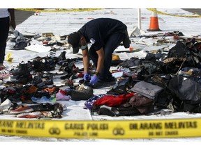 An investigator inspect debris from Lion Air flight JT 610 that crashed into the Java sea on Monday, at Tanjung Priok Port in Jakarta, Indonesia, Friday, Nov. 2, 2018. New details about the crashed aircraft previous flight have cast more doubt on the Indonesian airline's claim to have fixed technical problems as hundreds of personnel searched the sea a fifth day Friday for victims and the plane's fuselage.