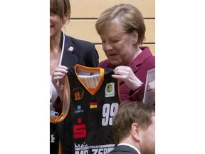 German Chancellor Angela Merkel holds a shirt as she visits the NINERS German first divisioner basketball youth teams (under 16 years and under 19 years) during her one-day visit in Chemnitz, eastern Germany, Friday, Nov. 16, 2018. Chemnitz has seen a few federal politicians show their faces since a 35-year-old local man was stabbed to death in August, allegedly by migrants, followed by a surge of violent right-wing protests.