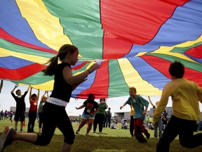 FILE - In this Thursday, April 25, 2013 file photo, elementary school third graders run under a rainbow colored tarp during the 15th Annual Kansas Kids Fitness Day, in Hutchinson, Kan. New federal guidelines released on Monday, Nov. 12, 2018, advise that children as young as age 3 should move more, sit less and get more active, and that any amount and any type of exercise helps health.